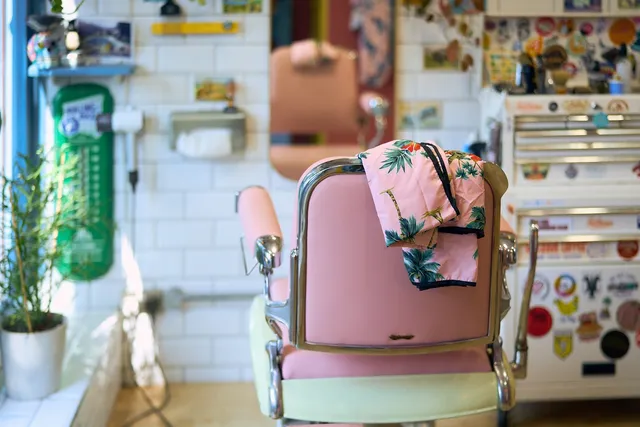 A pink vintage barber chair with a palm-print cape at Tallboys
