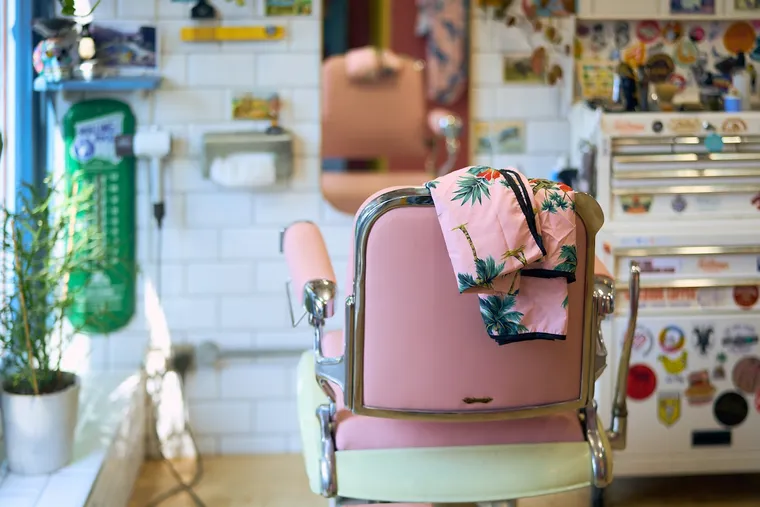 A pink vintage barber chair with a palm-print cape at Tallboys, Brighton